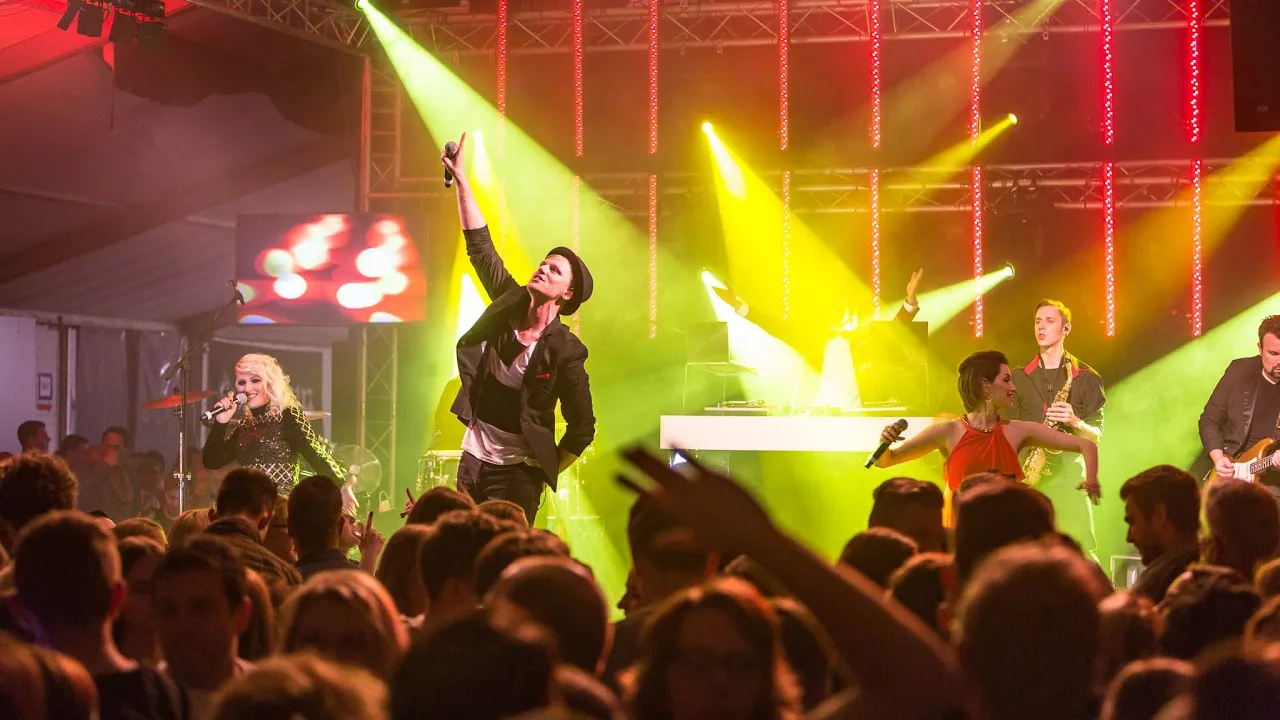 Live-Musik-Performance mit Gesang, Saxophon, energiegeladenem Publikum und bunter Lichtshow.